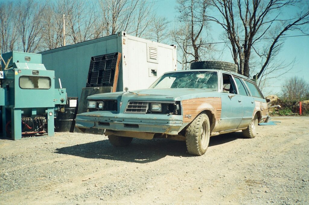 A battered car sits in a junkyard.