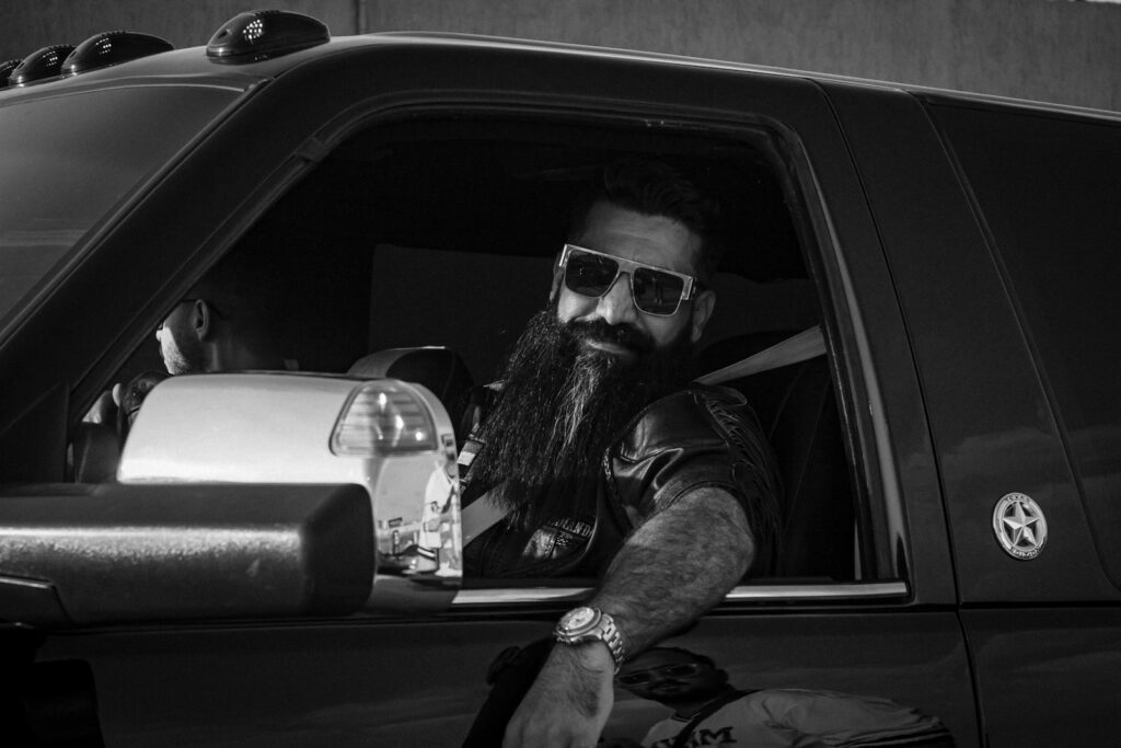 Man with long beard in sunglasses driving truck