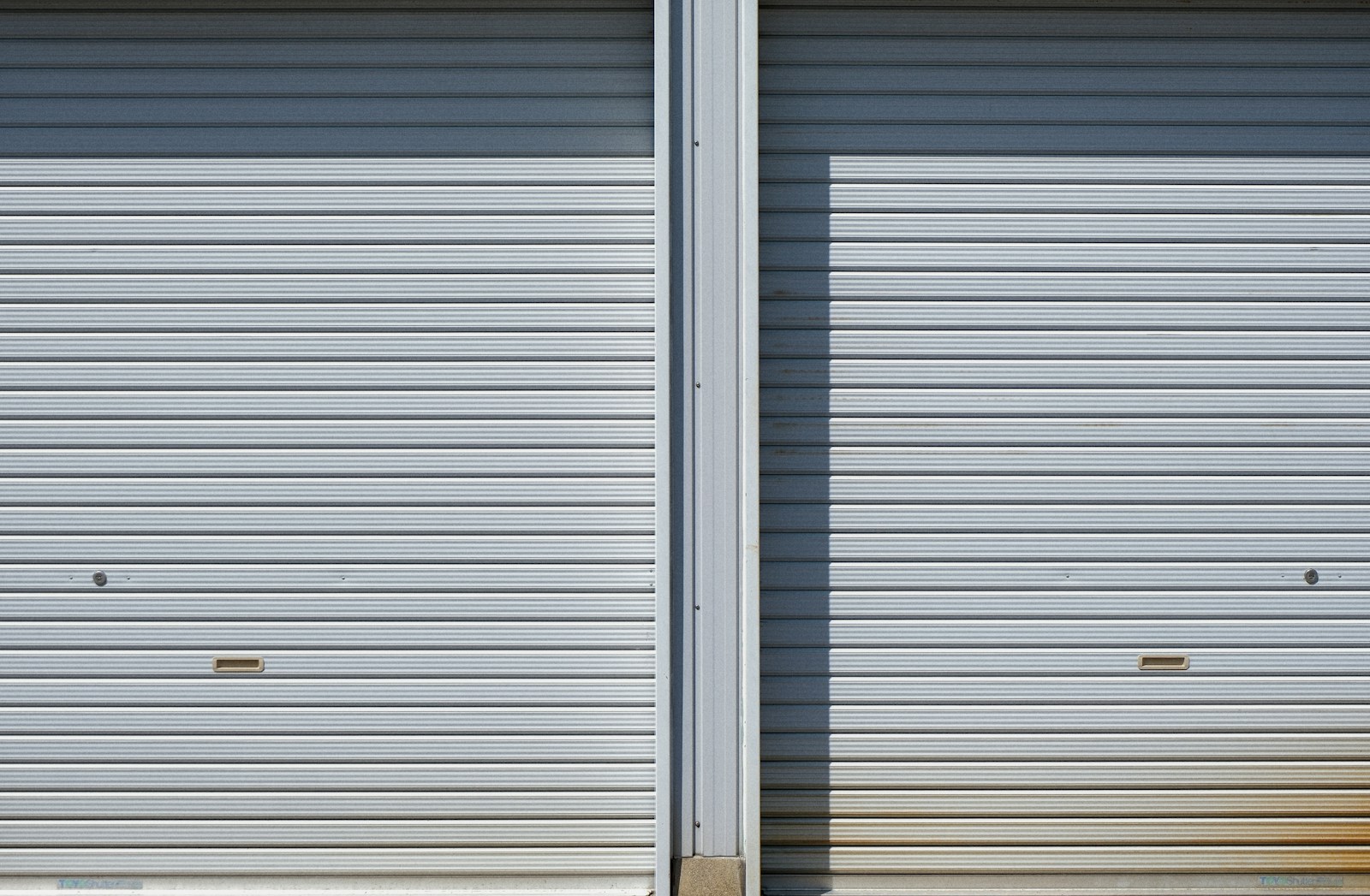 Two closed metal roll-up garage doors side by side.