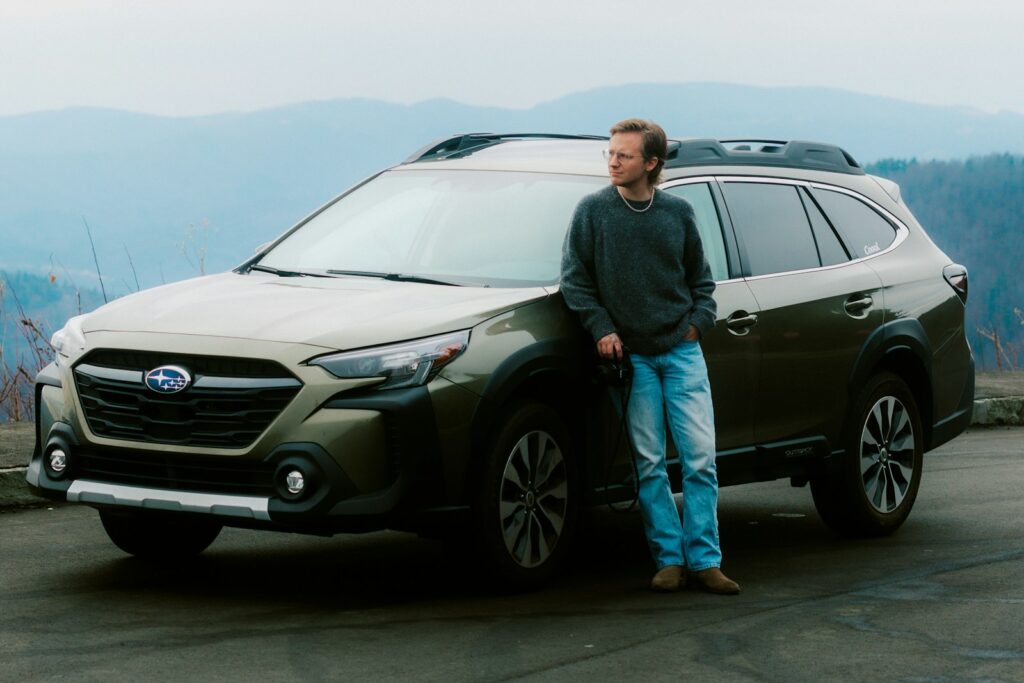 Man leaning on a car with mountains behind him