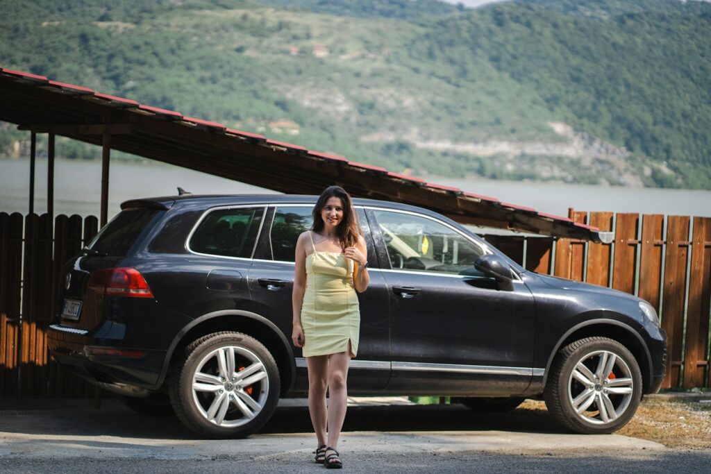 a woman in a yellow dress standing in front of a car