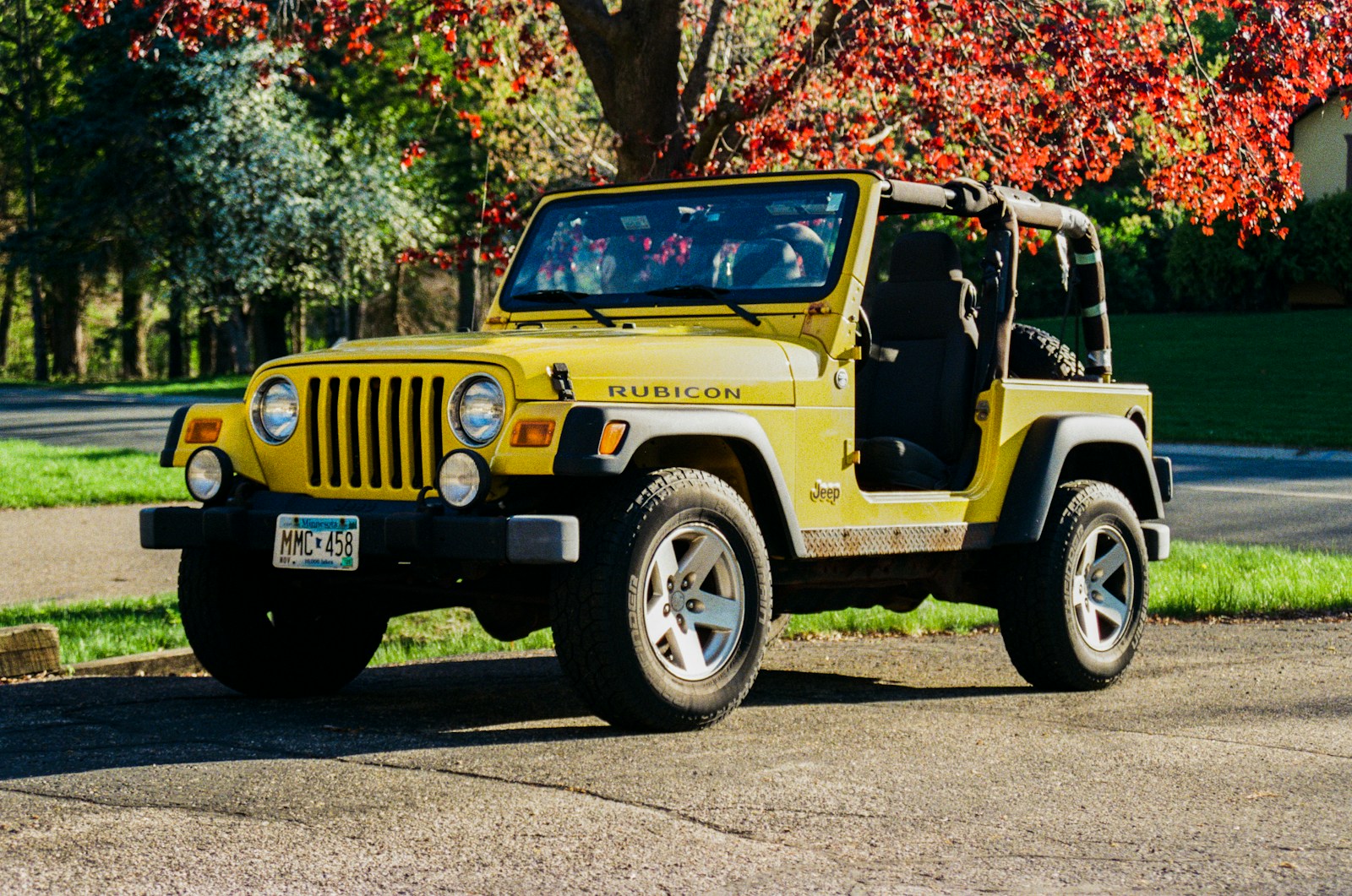 Here is a caption for the image: a yellow jeep wrangler sits outdoors.