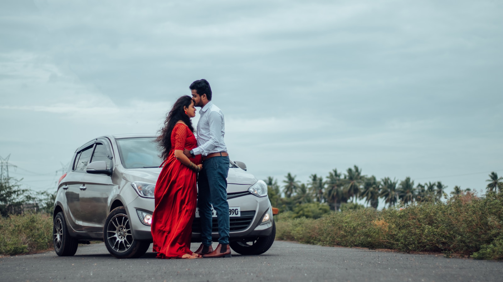 a man and woman standing next to a car