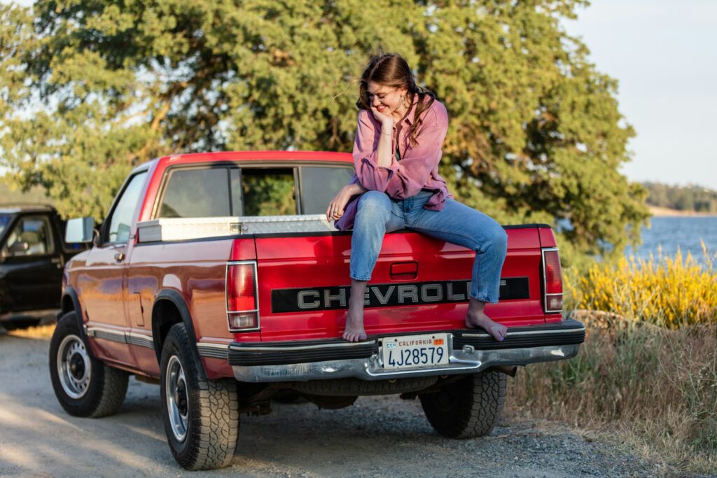 A woman sitting on the back of a red pick up truck