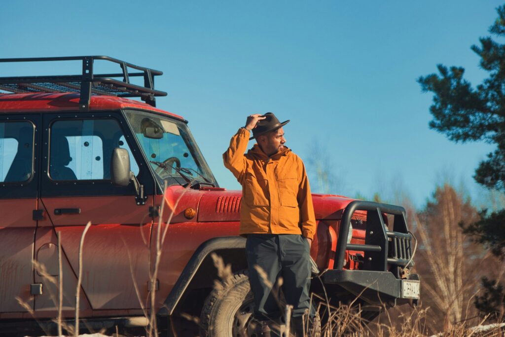 Man in hat next to a red off-road vehicle