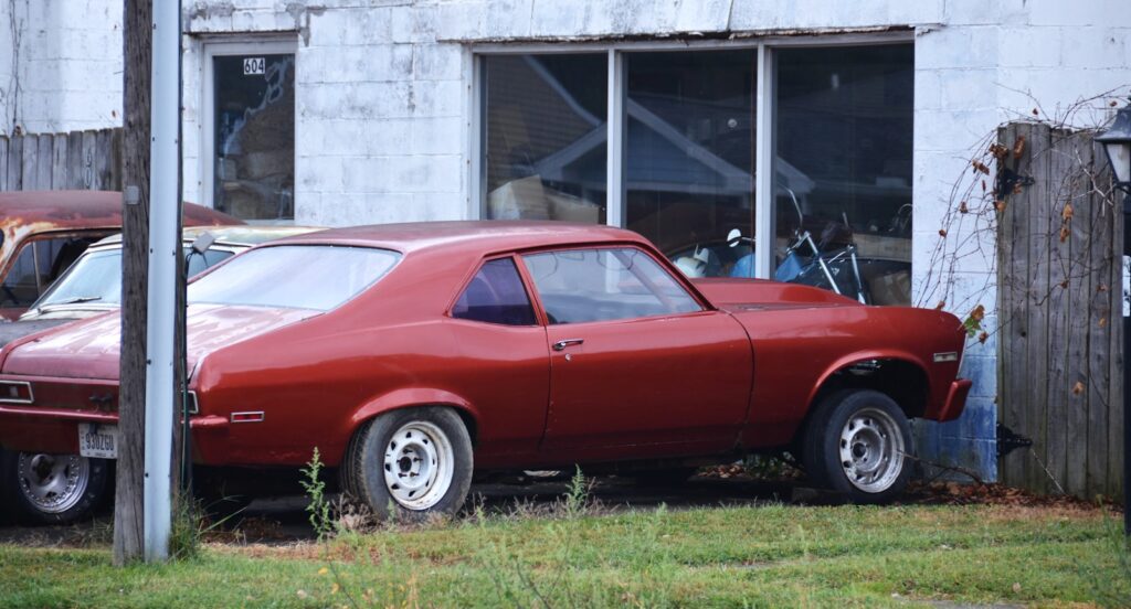 A red classic car parked outside building