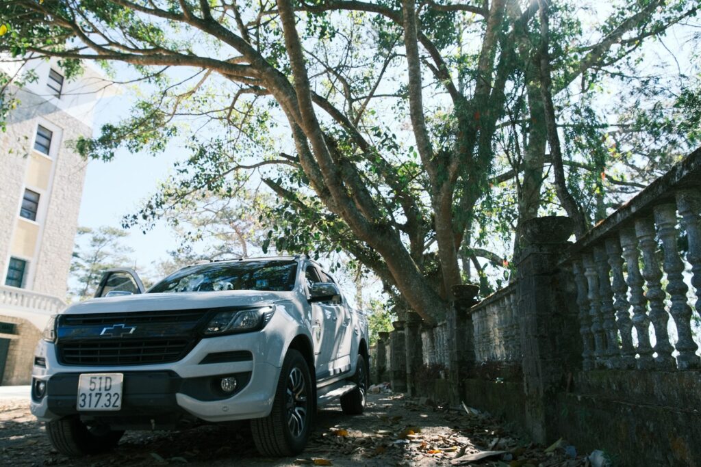 a white pick up truck parked next to a tree