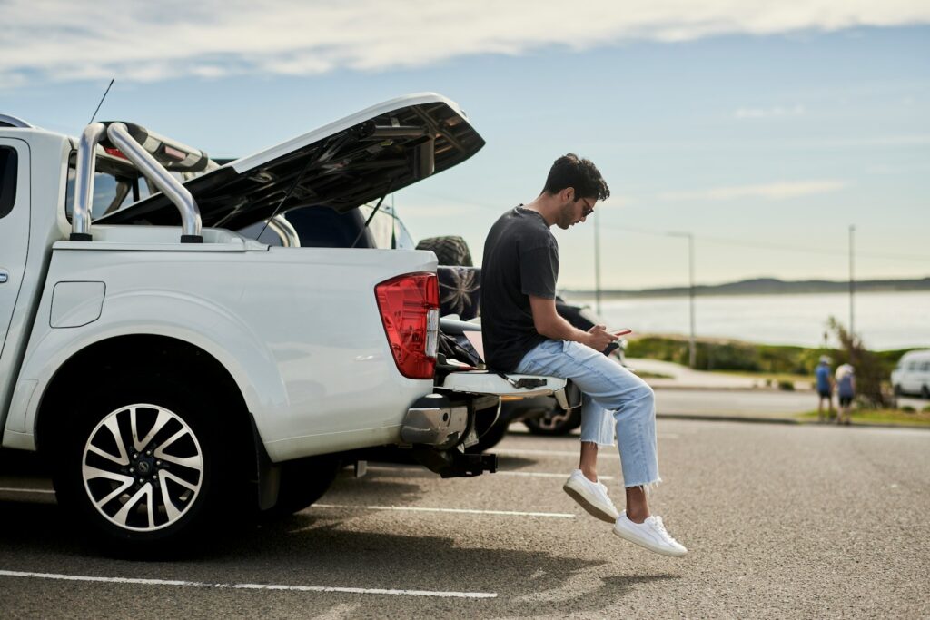 man sitting on car looking at phone