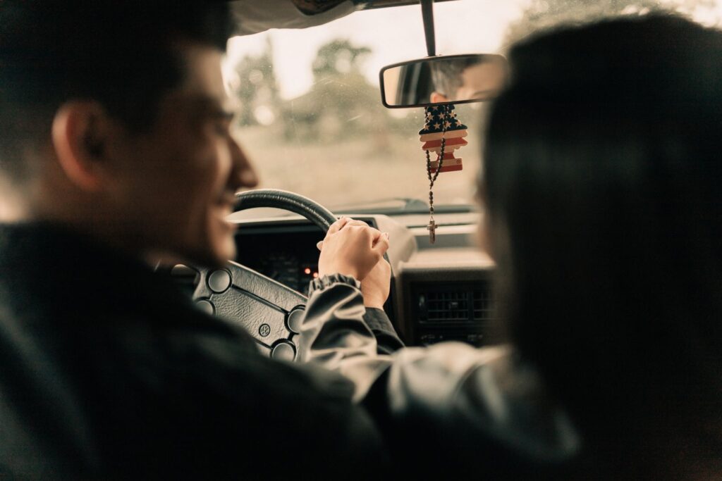 Romantic moment of a couple holding hands inside a car during a relaxed drive.