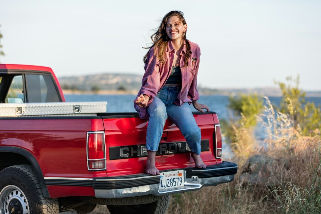 A woman sitting on the back of a red pickup truck