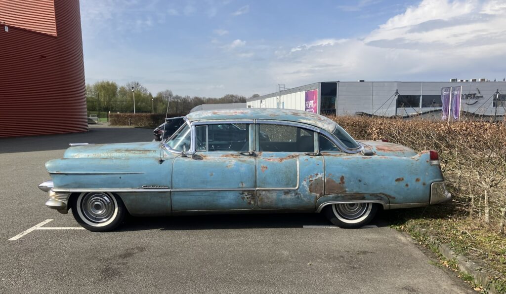 A weathered blue vintage car parked outside a building.