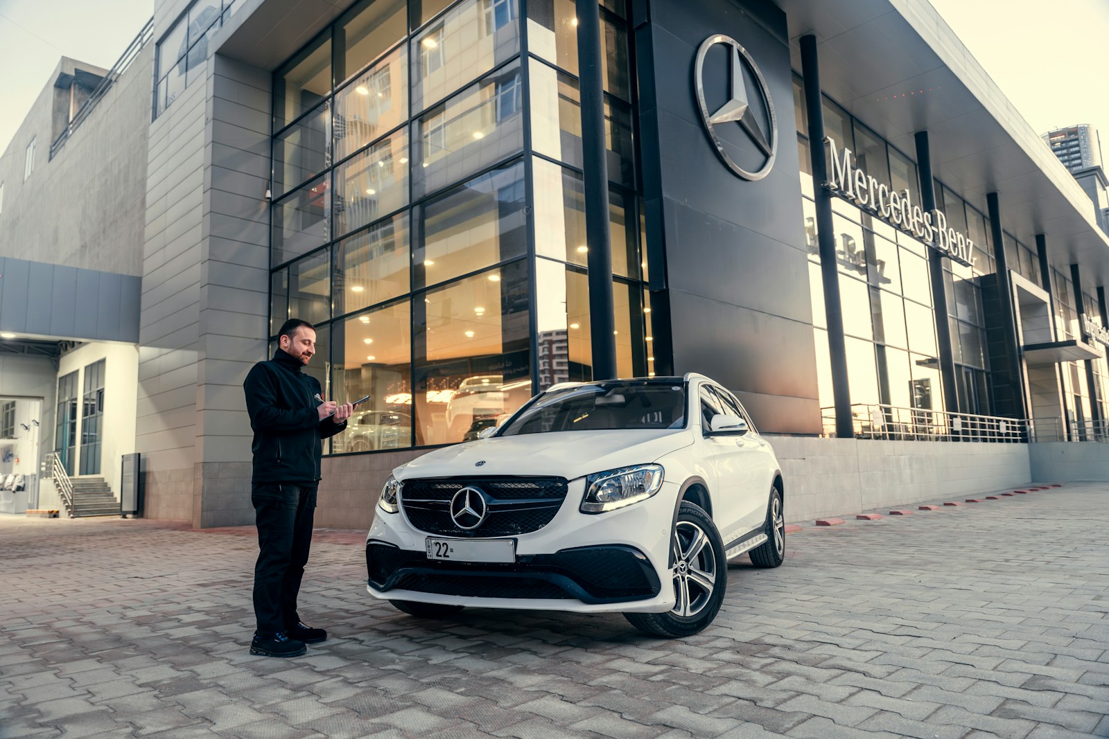 Man standing by a white mercedes-benz suv outside dealership.