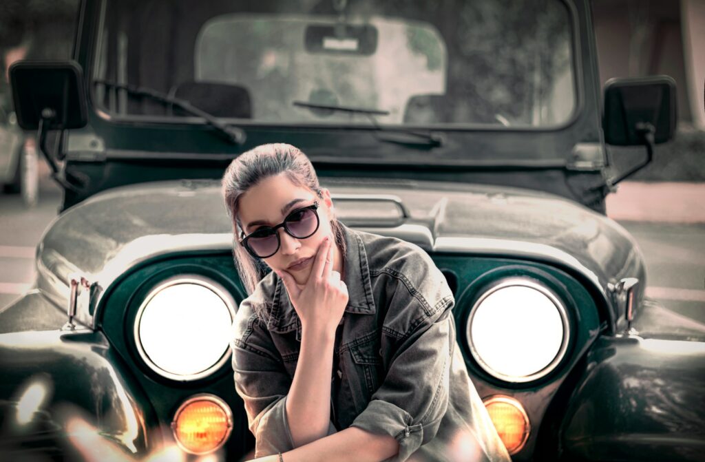 a woman sitting on the front of a green jeep