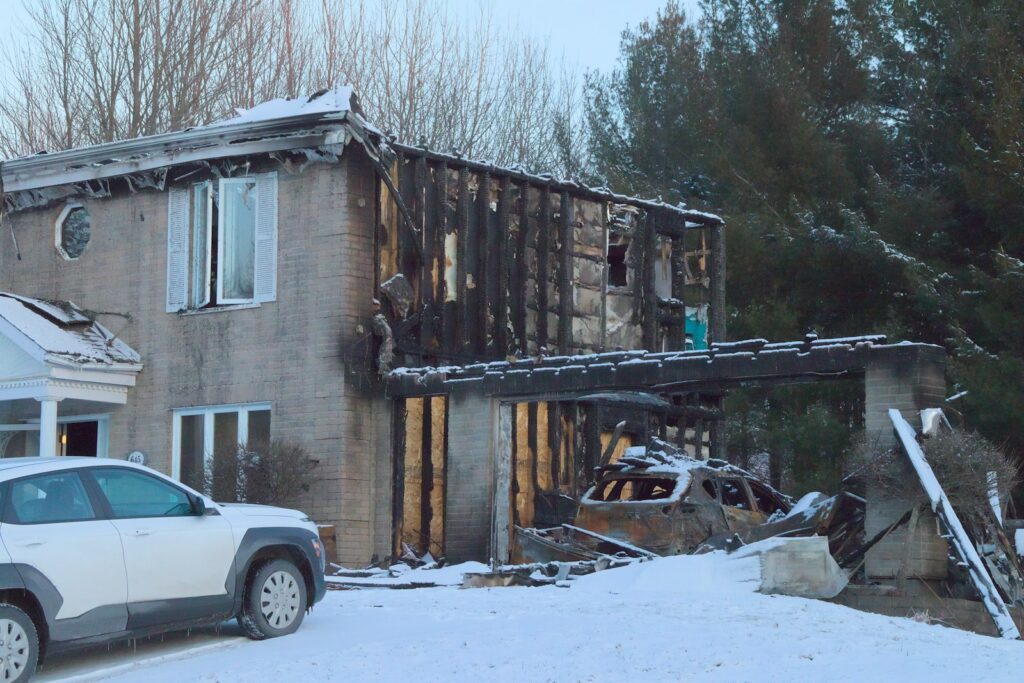 A car parked in front of a fire damaged house