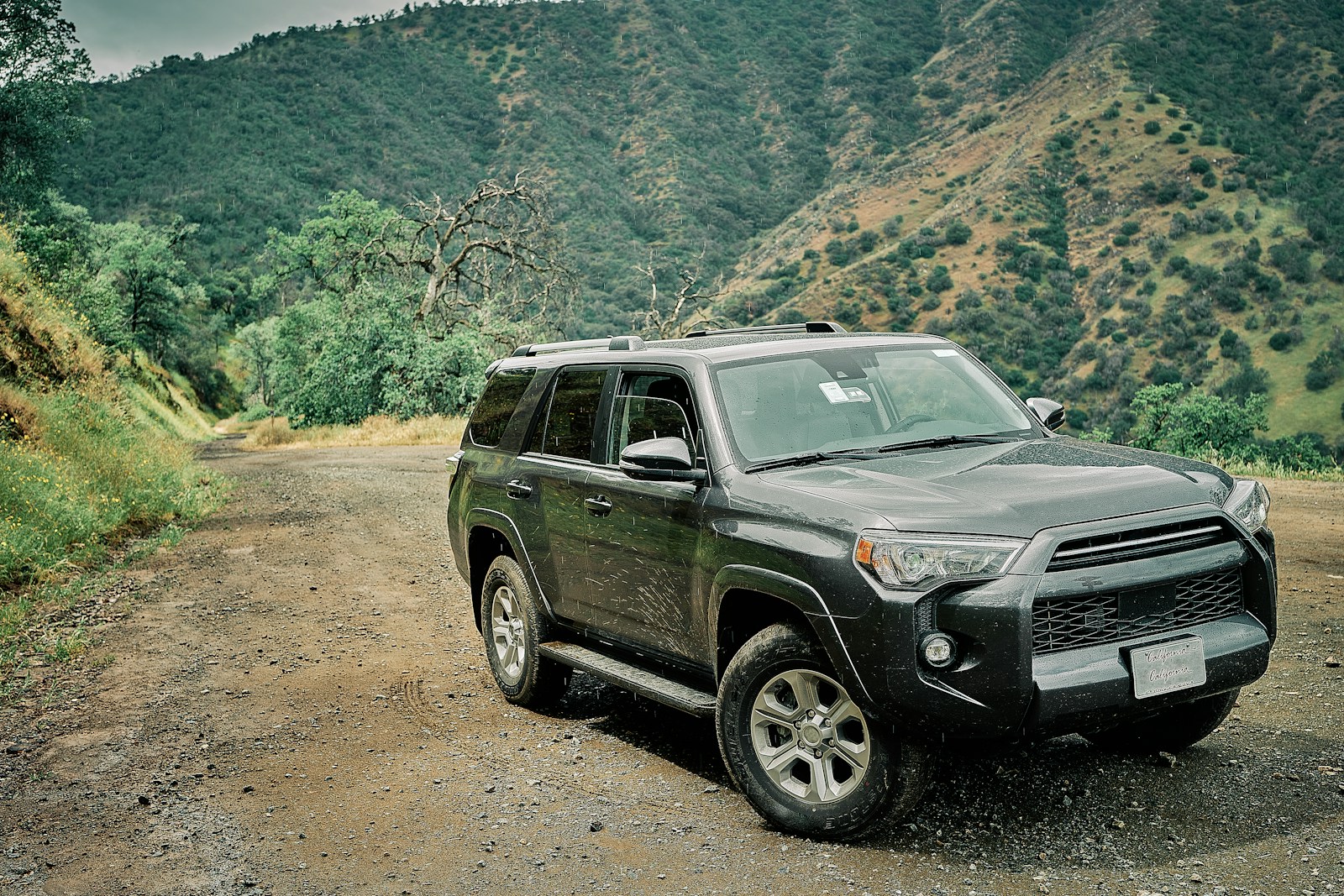 a black suv is parked on a dirt road