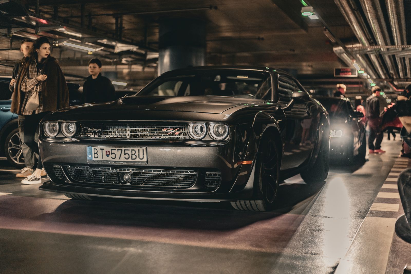Elegant sports car in underground garage, Bratislava, Slovakia. Urban vibe with people nearby.
