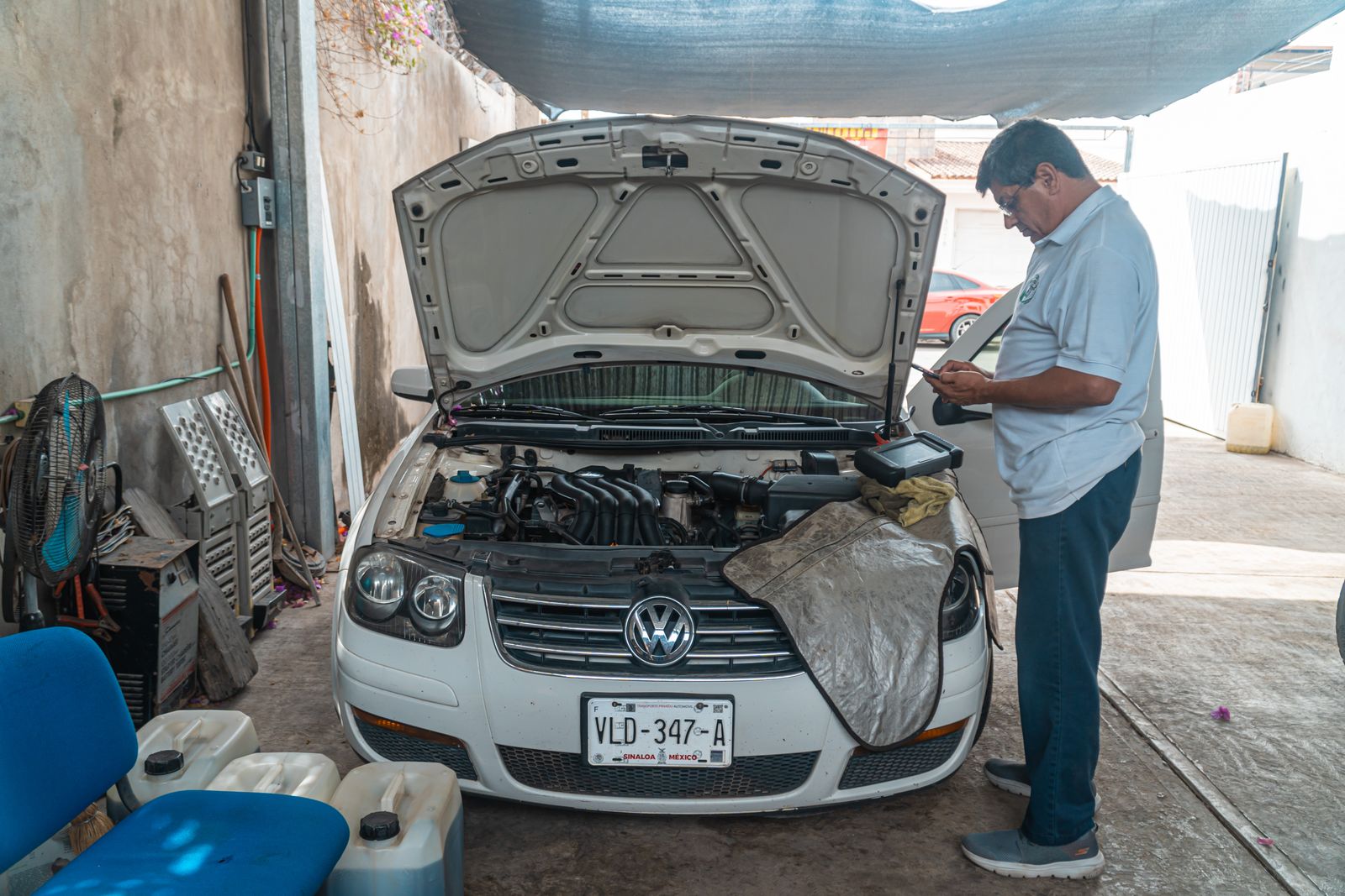 A mechanic examines a Volkswagen engine in a garage setting, focusing on car maintenance.