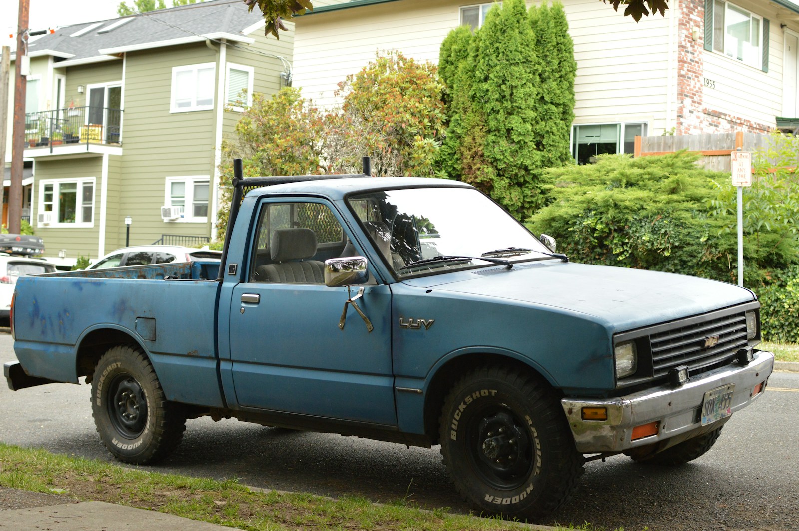 An old blue pickup truck parked on a residential street.