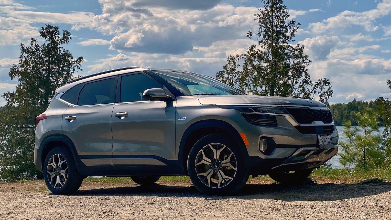 a silver suv parked on a gravel road next to a body of water