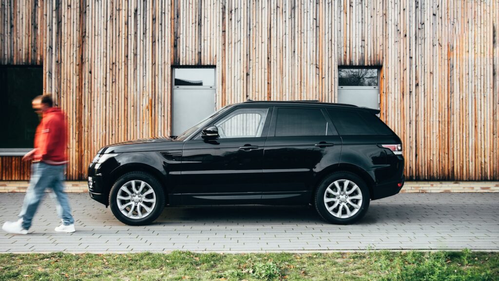 black suv parked beside brown wooden wall