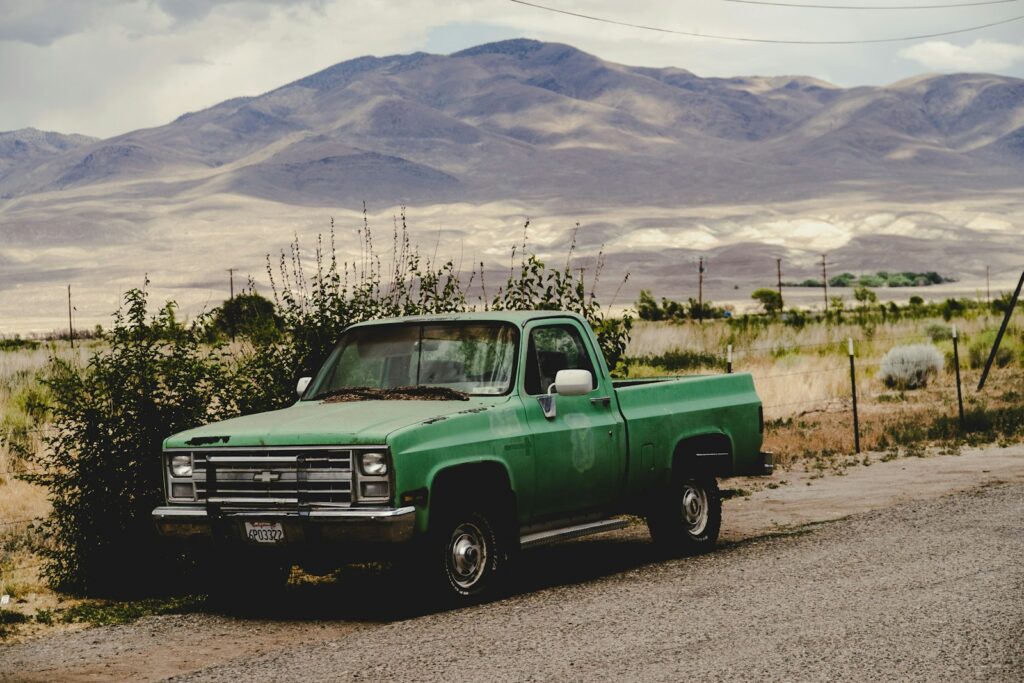 a green pick up truck parked on the side of a road