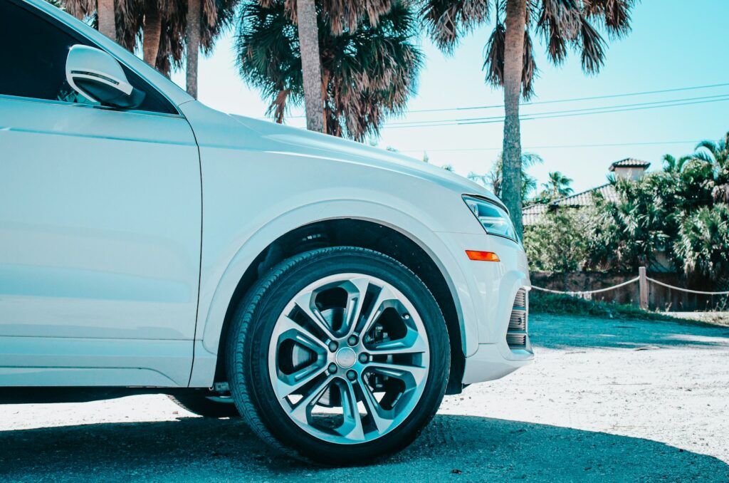 a white car parked in a driveway next to palm trees