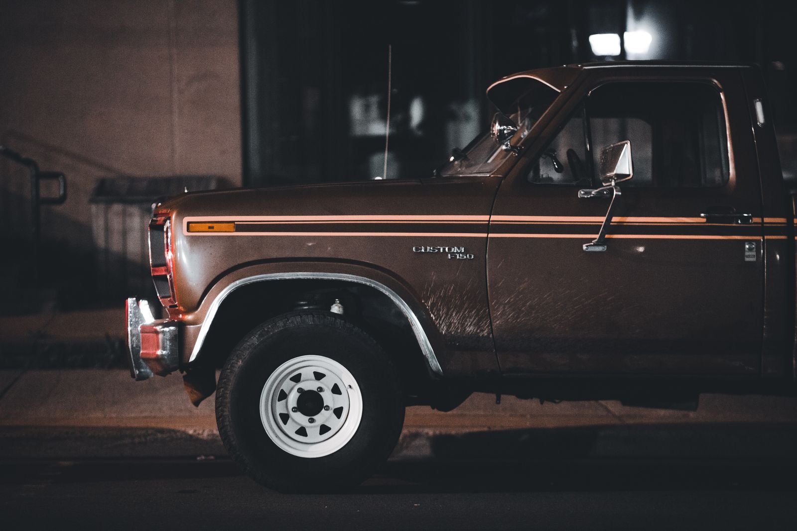 Classic Ford pickup truck parked on a city street at night, showcasing vintage style and nostalgia.
