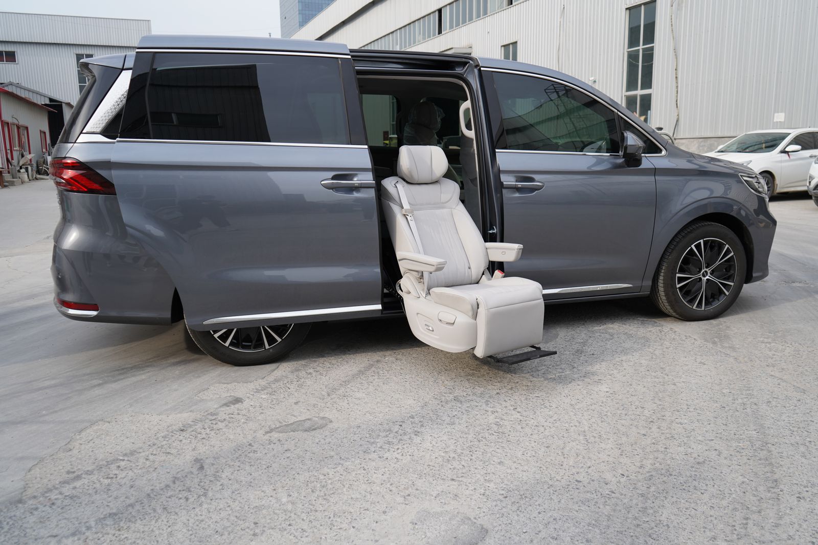 Gray luxury minivan featuring an open door with a reclining massage seat in an urban setting, showcasing comfort and style.
