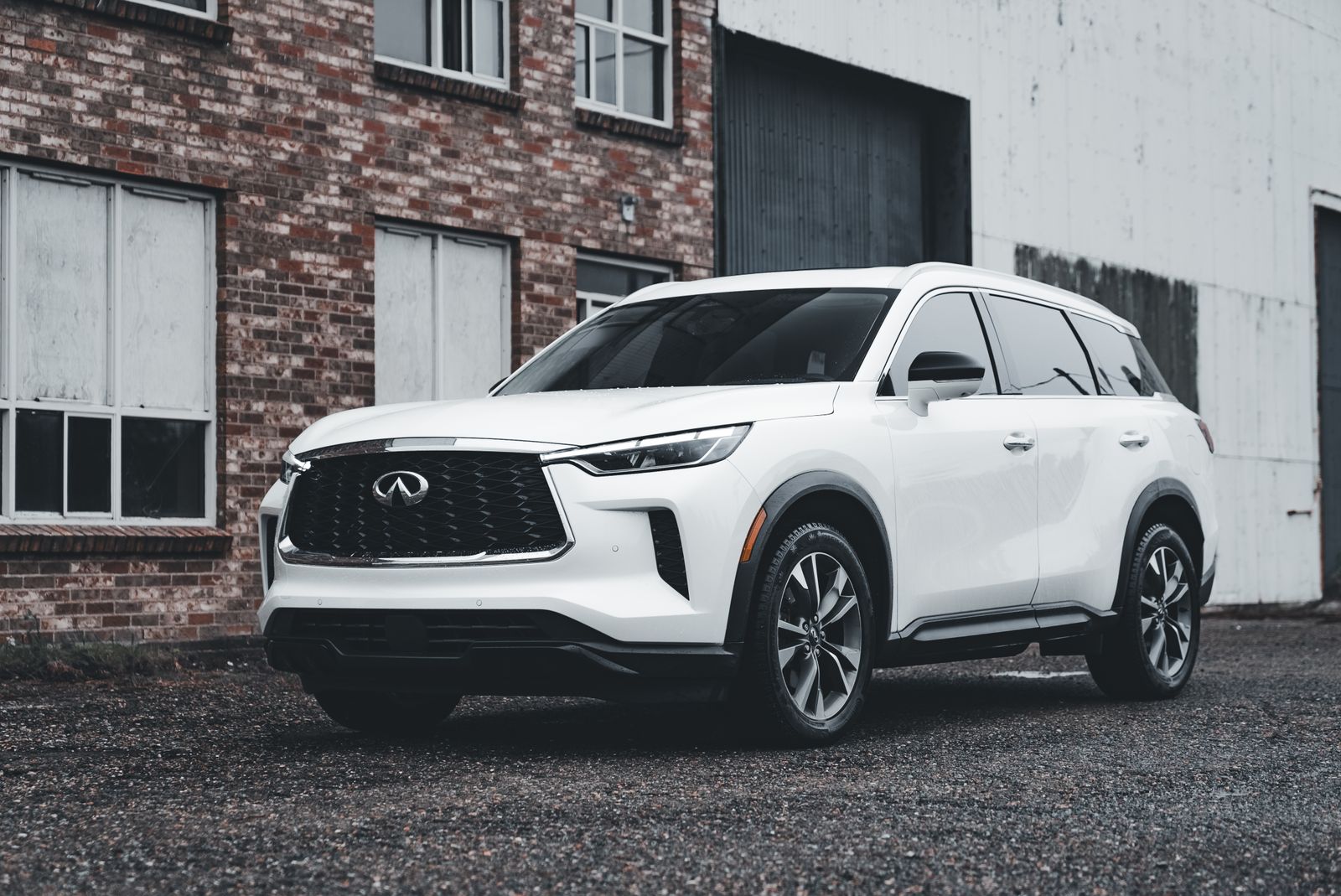 White luxury SUV parked outdoors in front of a brick building, showcasing modern automotive design.