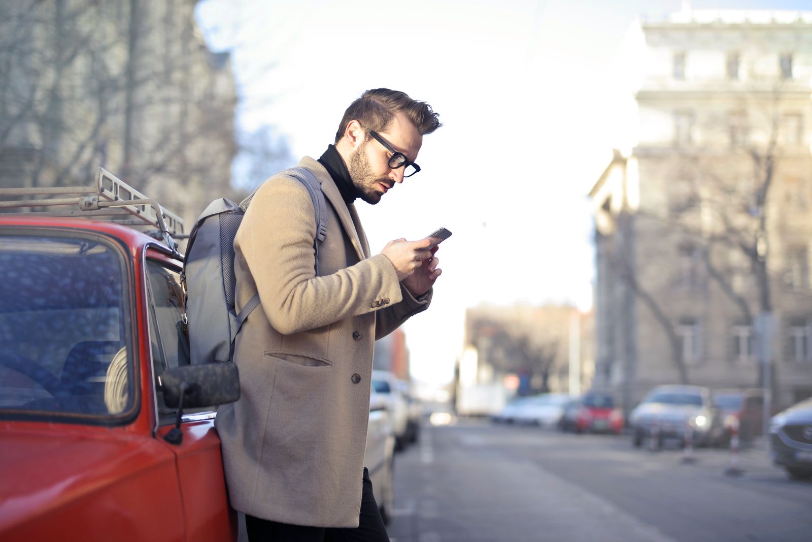 Man with backpack using smartphone on urban street in Budapest.