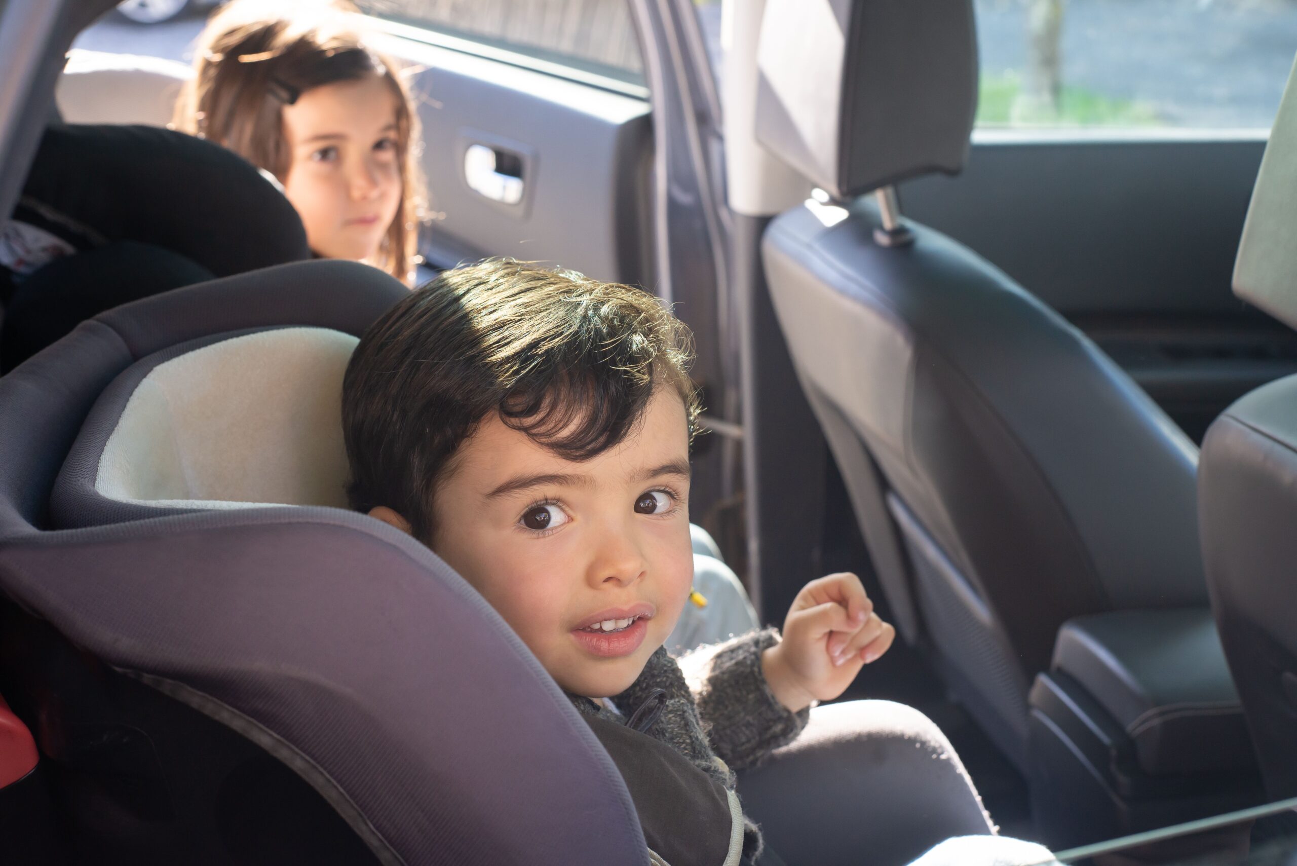 Child sitting in a car seat in the back row of a vehicle