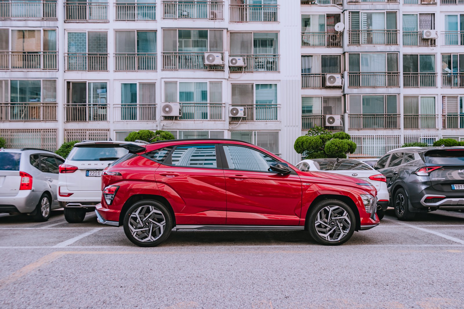 Red car parked in a lot with apartment buildings behind