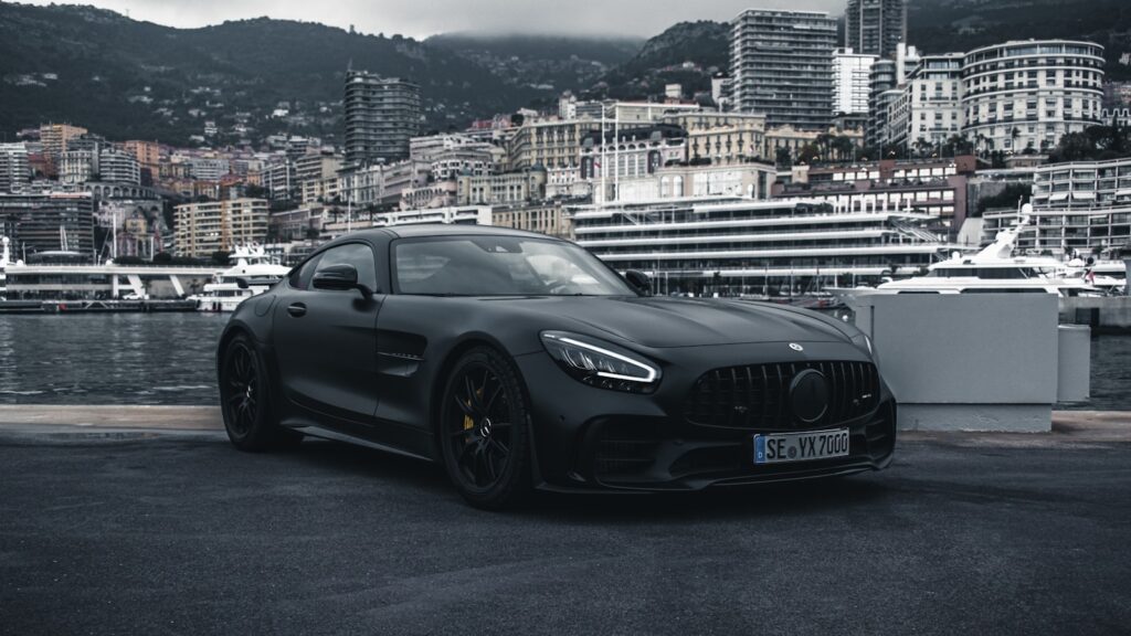 A matte black Mercedes-AMG GT sports car parked on a harbor quay in Monaco