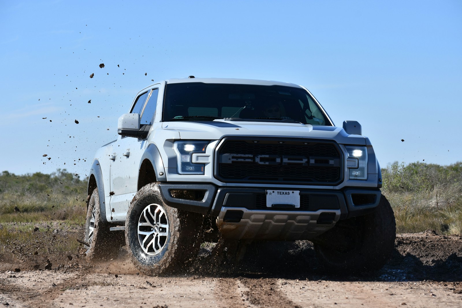 a white truck is driving through the mud
