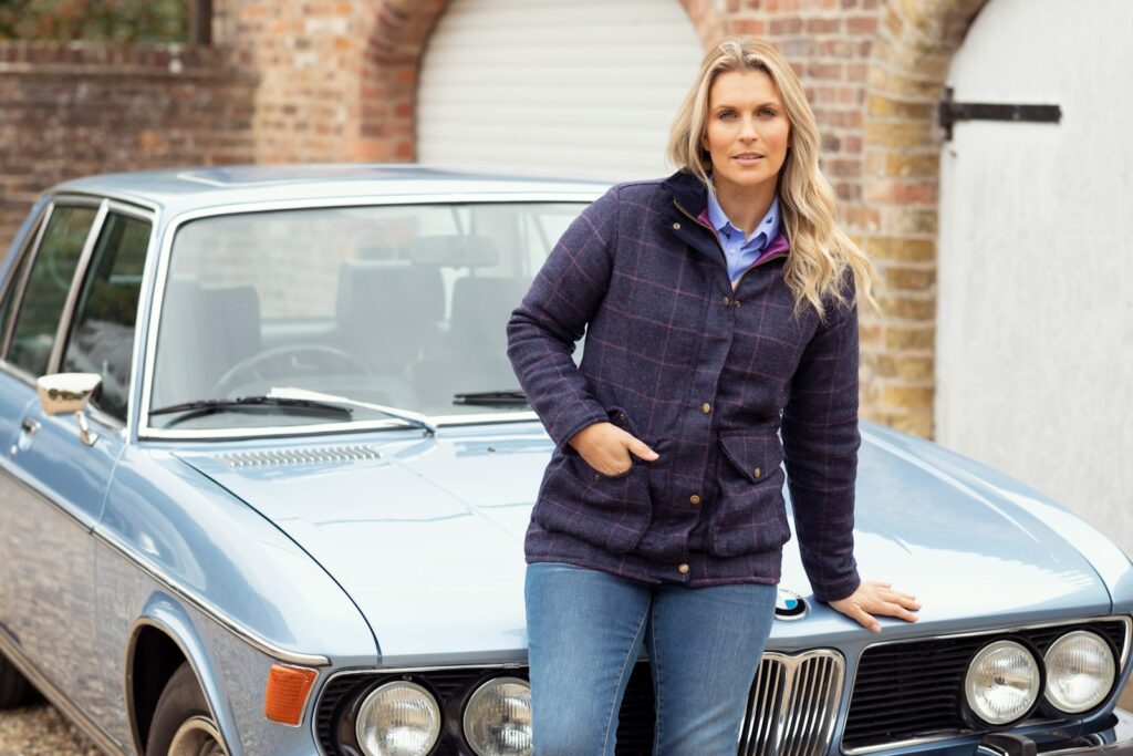 a woman standing next to a blue car