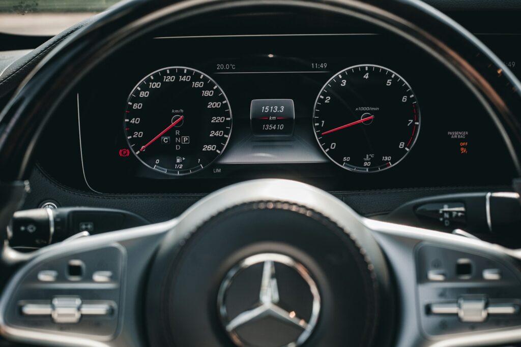 A mercedes-benz car dashboard with speedometer and steering wheel.
