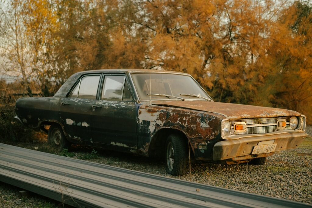 A rusted out car sitting on the side of a road