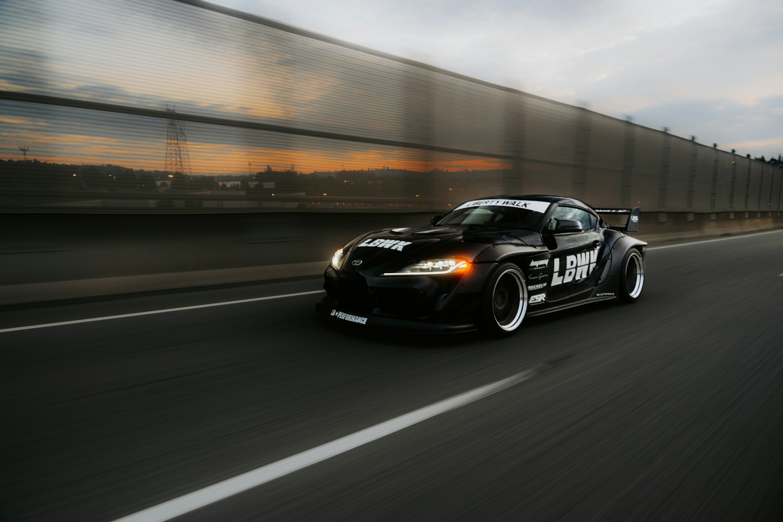 A fast black sports car races down the highway