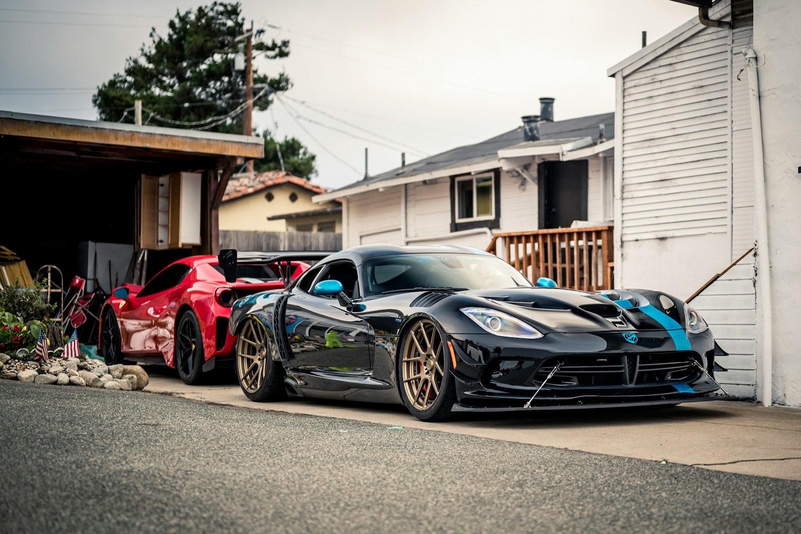 Two modified sports cars parked outside a garage