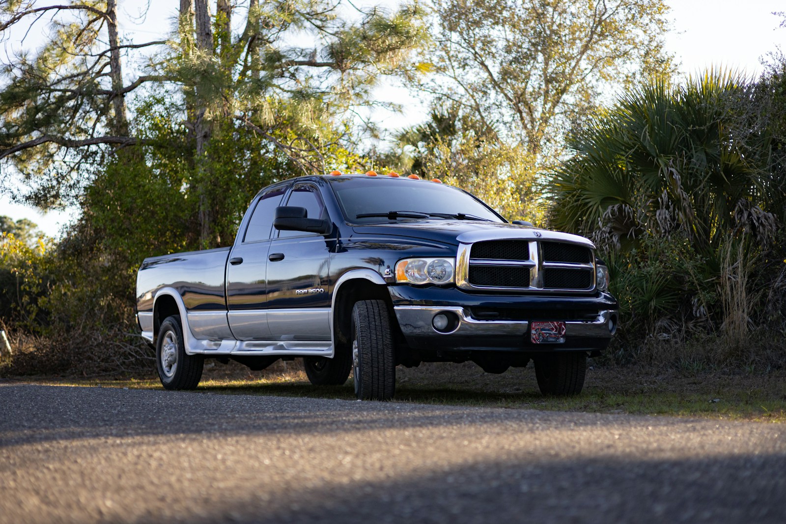 Dark blue pickup truck parked on a gravel road.