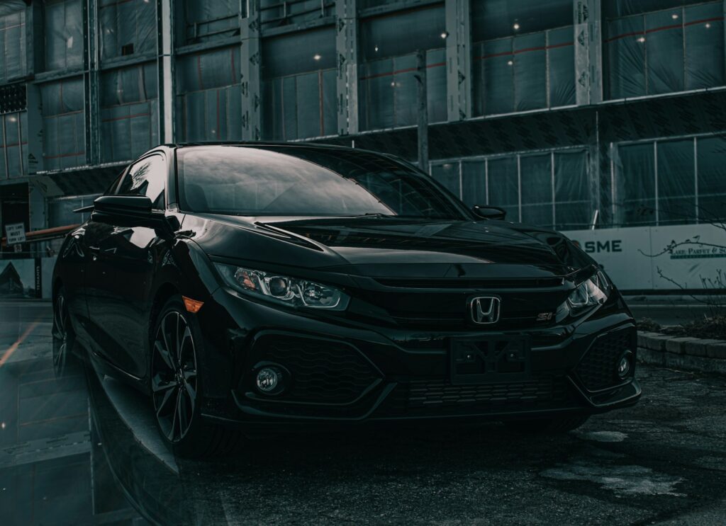 A black Honda Civic Si parked in front of a building under construction