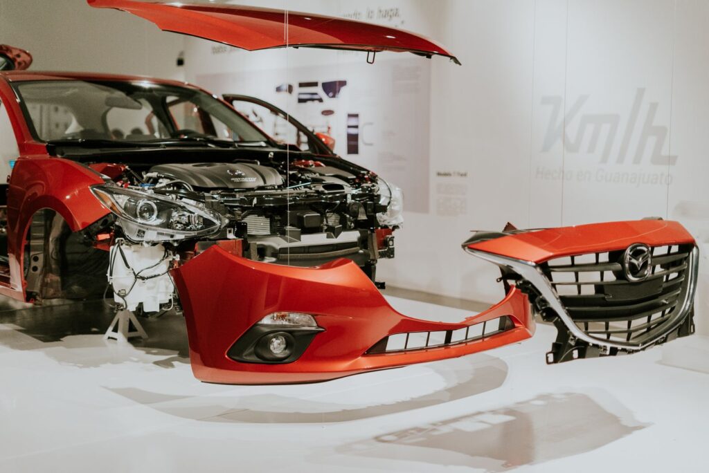 Explore a detailed view of a partially disassembled red Mazda 3 showcased at an auto exhibition.