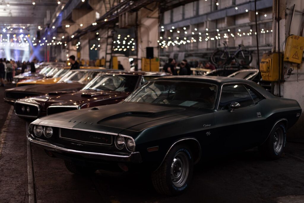 Lineup of classic cars in an industrial indoor setting with ambient lighting.
