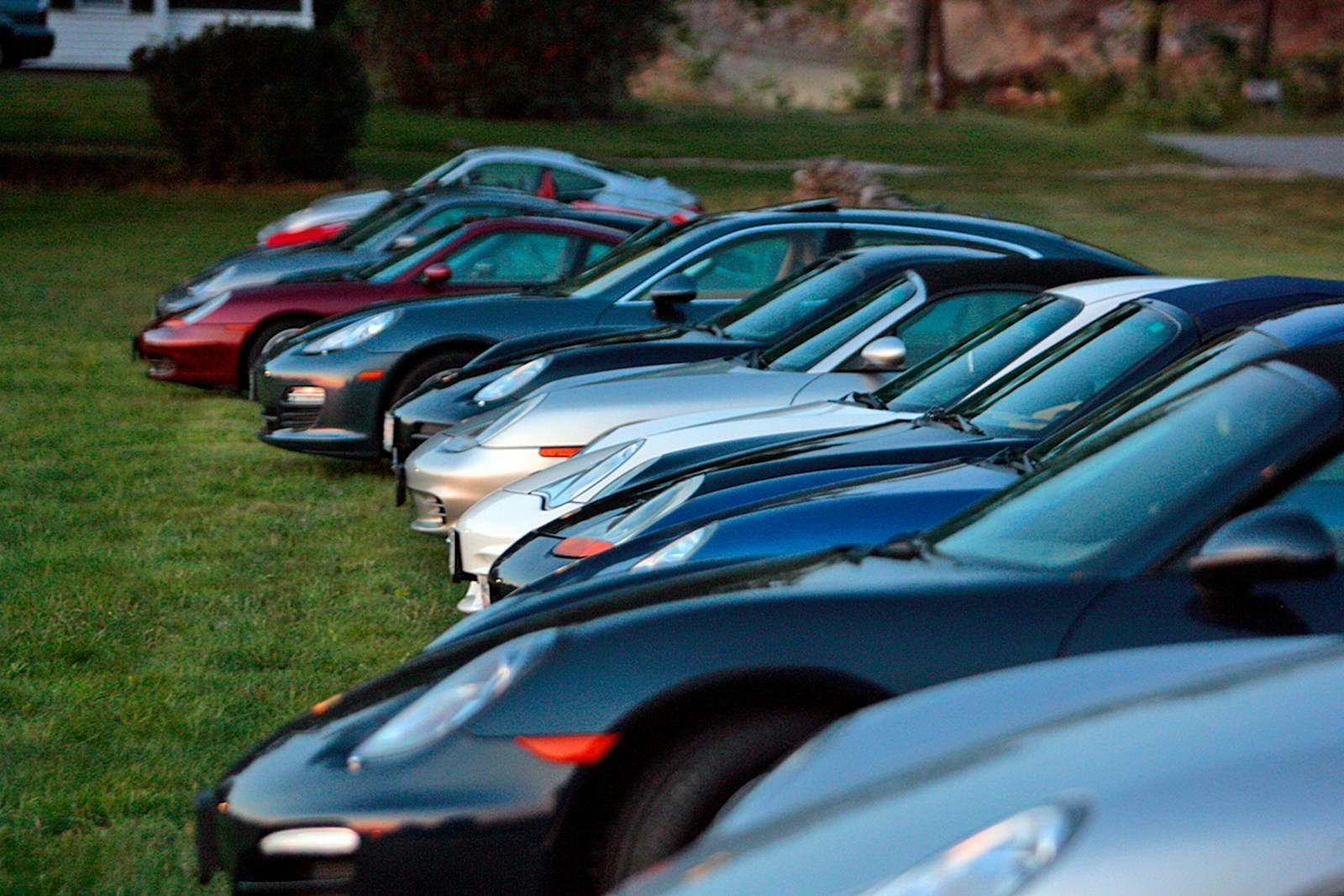 a row of parked cars sitting on top of a lush green field