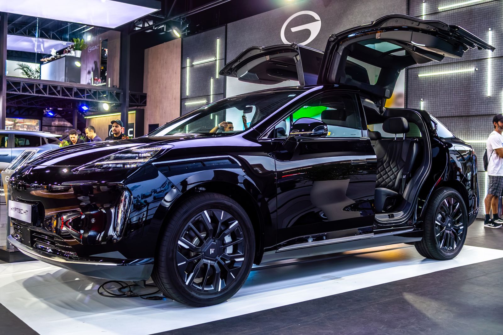 Sleek black electric SUV displayed with gullwing doors at São Paulo auto show, showcasing modern technology.