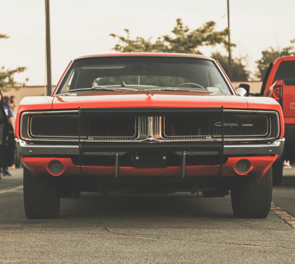a red car parked in a parking lot next to a red truck