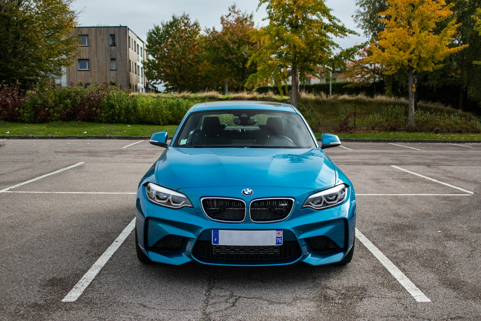 A blue sports coupe parked in a parking lot.