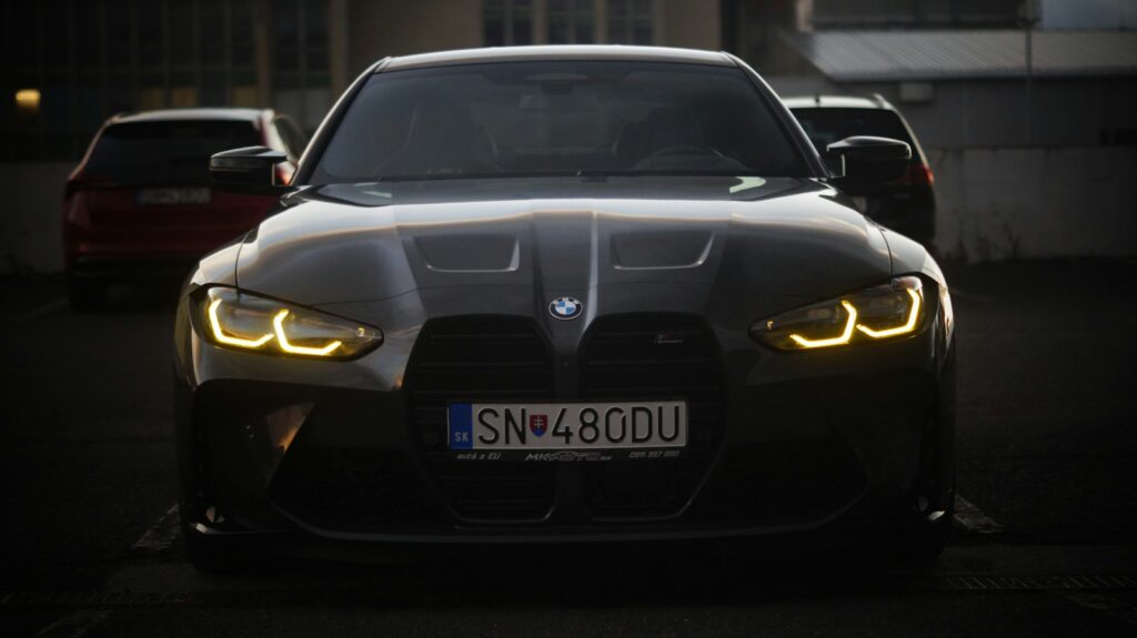The front of a black car with its lights on