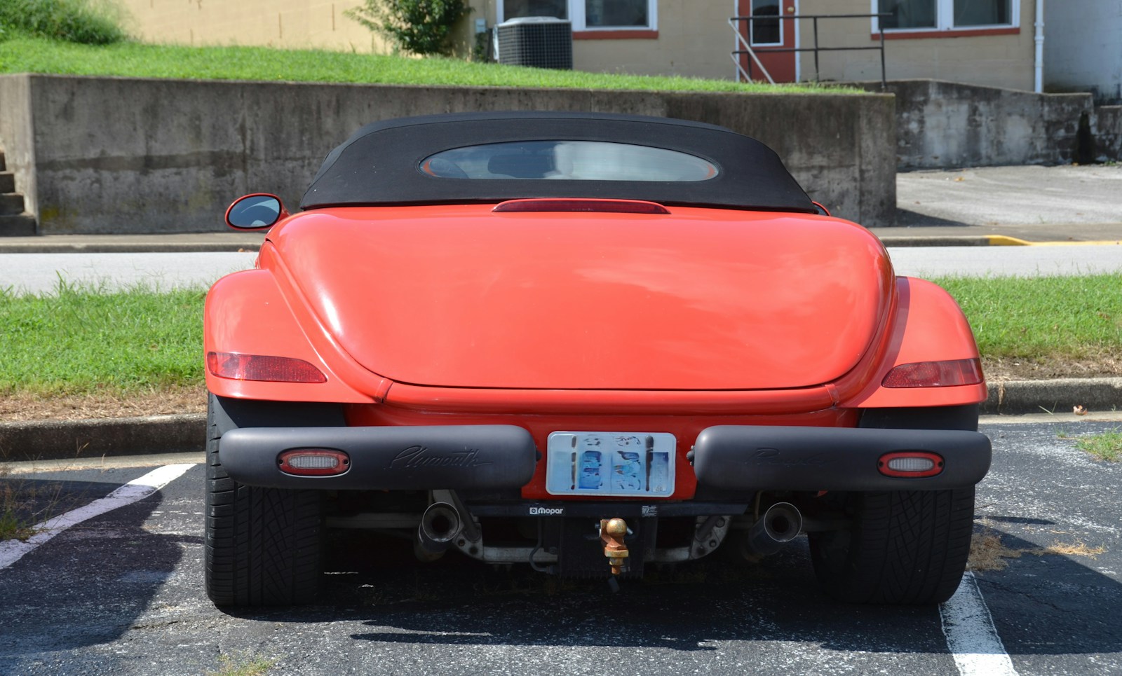 Rear view of a red convertible car with a black soft top parked outdoors