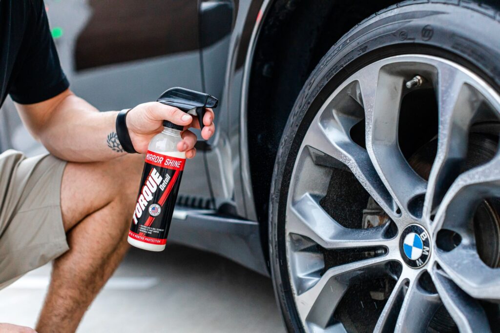 A person is applying tire shine on a BMW wheel, showcasing a luxury car's shiny finish.